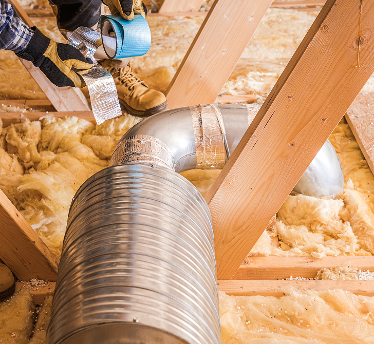 Installer sealing a ventilation duct running through an insulated loft